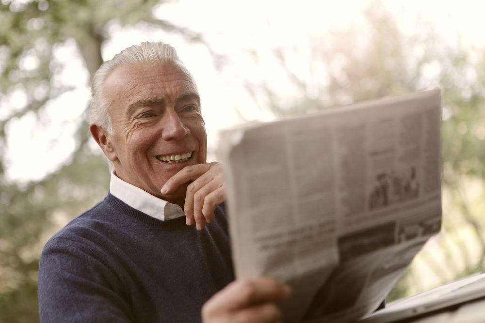 a man reading a newspaper getting a good idea from a for-profit professional development brand